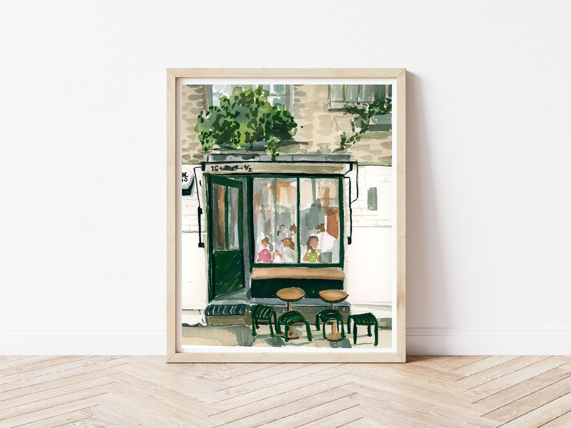 London cafe print of painting by Medjool Studio. Print of original gouache painting of a coffee shop in London, England full of customers and two small tables with stools out front.